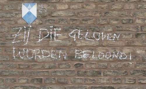 Foto van een (kerk)muur waarop 'Zij die geloven worden beloond' staat geschreven.